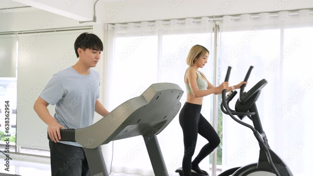 Asian man and beautiful woman walking on treadmill Asian man and beautiful woman walking on treadmill