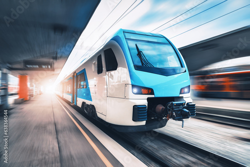 High speed train in motion on the railway station at sunset. Blue modern intercity passenger train with motion blur effect on the railway platform. Railroad in Europe. Commercial transportation © den-belitsky