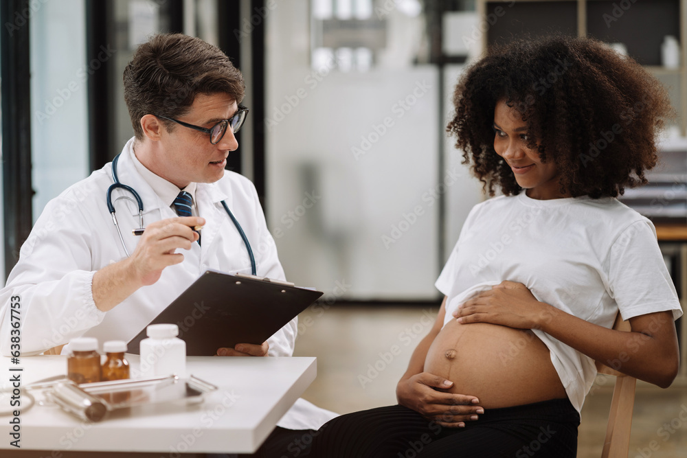 Happy pregnant woman has appointment with doctor at clinic. male medic specialist with stethoscope listens to baby's heartbeat in mother's belly. Pregnancy, health care concept. Happy pregnant woman has appointment with doctor at clinic. male medic specialist with stethoscope listens to baby's heartbeat in mother's belly. Pregnancy, health care concept.