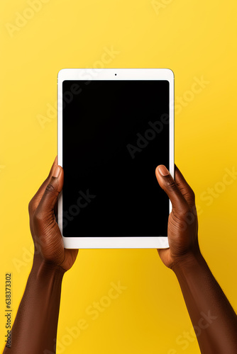 Hand holding tablet with mockup blank screen isolated on yellow background