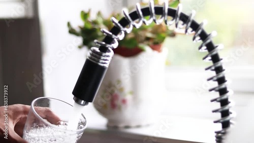 Person filling glass by tap water. Holding glass under running faucet.  Ecological and healthy drink. close up