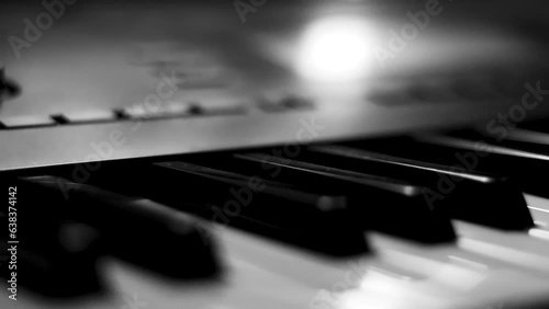 Close-up macro pan of black and white piano keys. Elegant piano keys moving, close up.Tracking backwards shot. Slow motion. Black and white keys. Reflection on piano keys. Music, learn, artistic