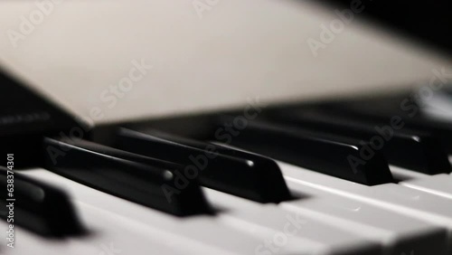 Close-up macro pan of black and white piano keys. Elegant piano keys moving, close up.Tracking backwards shot. Slow motion. Black and white keys. Reflection on piano keys. Music, learn, artistic