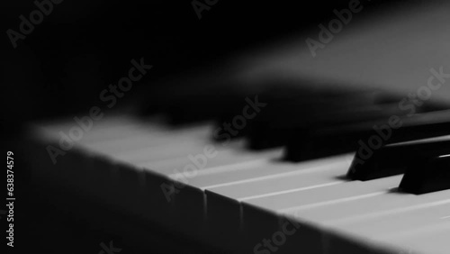 Close-up macro pan of black and white piano keys. Elegant piano keys moving, close up.Tracking backwards shot. Slow motion. Black and white keys. Reflection on piano keys. Music, learn, artistic