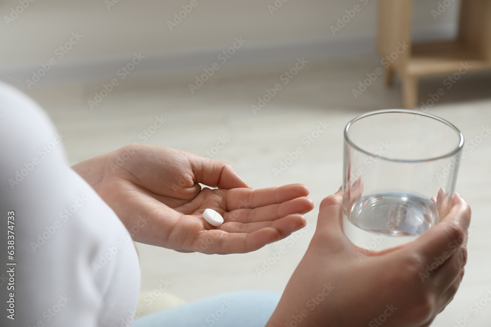 Woman with glass of water and pill on blurred background, closeup Woman with glass of water and pill on blurred background, closeup