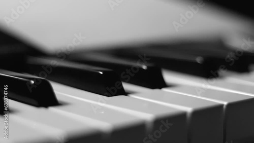 Close-up macro pan of black and white piano keys. Elegant piano keys moving, close up.Tracking backwards shot. Slow motion. Black and white keys. Reflection on piano keys. Music, learn, artistic