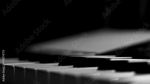 Close-up macro pan of black and white piano keys. Elegant piano keys moving, close up.Tracking backwards shot. Slow motion. Black and white keys. Reflection on piano keys. Music, learn, artistic