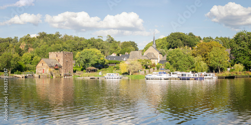 le village Chenillé-Champteussé en Anjou, en France sur les bords de la rivière Mayenne en region pays de la Loire. Des péniches de tourisme fluvial sur le bord de la rivière en été sous un ciel bleu.
