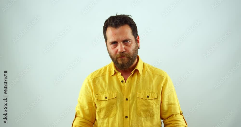 A middle-aged businessman is  in a studio, looking at the camera and wiping sweat from his brow. He appears to be feeling stressed or exhausted