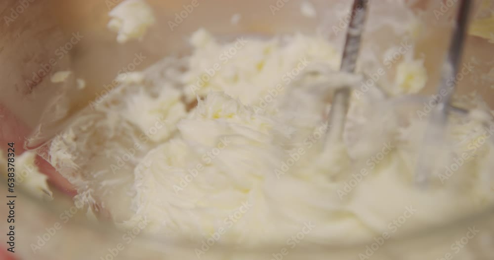 Mixing beating whipping butter in mixing bowl with hand mixer 