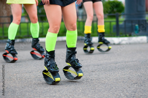 A group of sports girls in kangoo jumping boots outdoors. Close-up photo. Bright colors of sportswear. Selective focus.