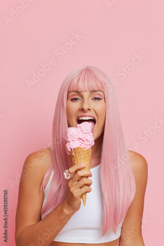 Pink style portrait og girl eating strawberry ice-cream, wearing long pink wig and white short top, tasty food concept, copy space
