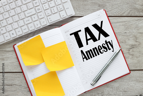 tax amnesty wooden background stickers on open notepad with text photo