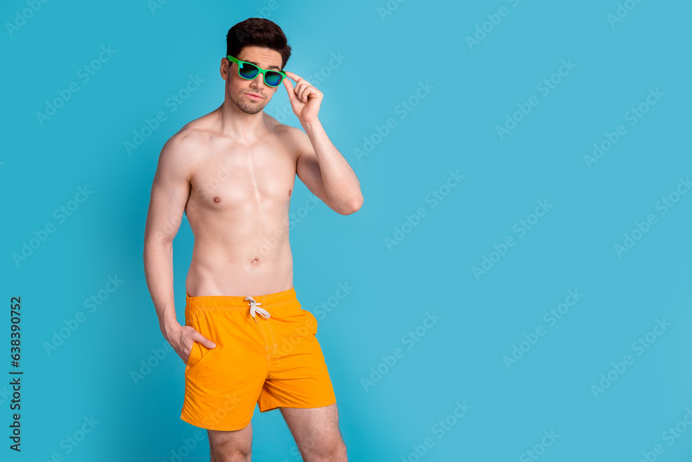 Photo portrait of nice young male confident touch sunglass wear trendy yellow shorts isolated on blue color background summer vacation Photo portrait of nice young male confident touch sunglass wear trendy yellow shorts isolated on blue color background summer vacation
