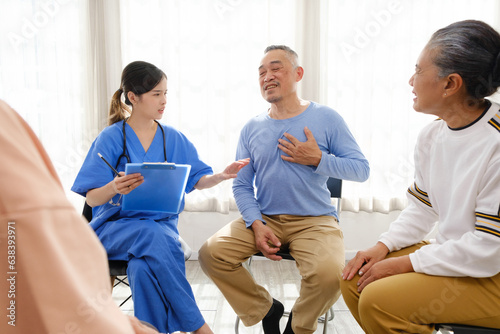The caregiver therapist sits with a group of Asian senior people in a circle for checking physical and mental health in a group elderly therapy session. The nursing home facilitates a support group