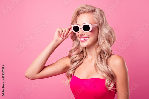 Portrait of cute lovely girl toothy smile arm touch sunglass empty space ad isolated on pink color background