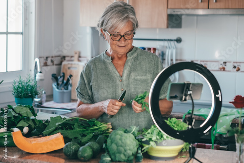 Принти на полотні Senior attractive woman streaming online by smartphone follows a vegetarian cooking class