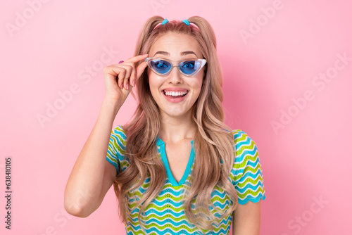 Portrait of impressed girl with tails dressed colorful suit touching blue sunglass staring open mouth isolated on pink color background © deagreez