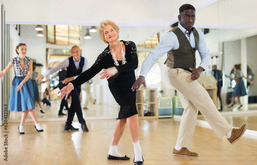 Lady learning to dance lindy hop with man in dance school