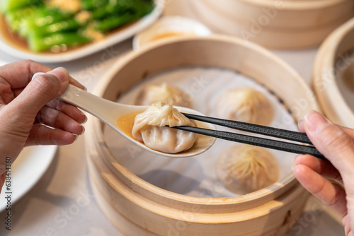 Photography Person taking a dumpling from spoon with chopsticks