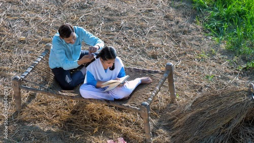 Indian mid aged village man braiding her teen daughter's hair with a ribbon - father-daughter bonding  village home. A loving single father helping her daughter get ready for school while his daugh... photo