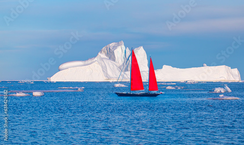 Giant iceberg near Kulusuk with lone yacht with red sails - Greenland, East Greenland