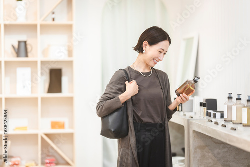 店舗で商品を手に取り選んでいる日本人女性/ショッピング
