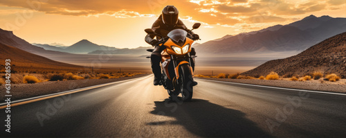 Driver riding motocycle on empty road in sunset light.  Panorama photo.