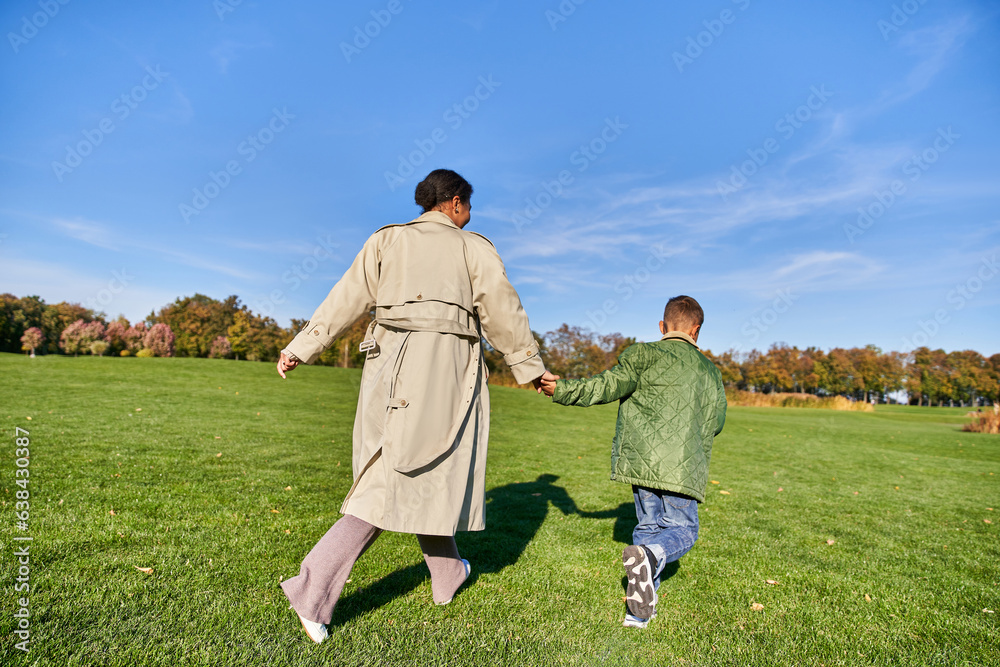 playful, african american woman running together with son in park, candid, sunny day in autumn playful, african american woman running together with son in park, candid, sunny day in autumn