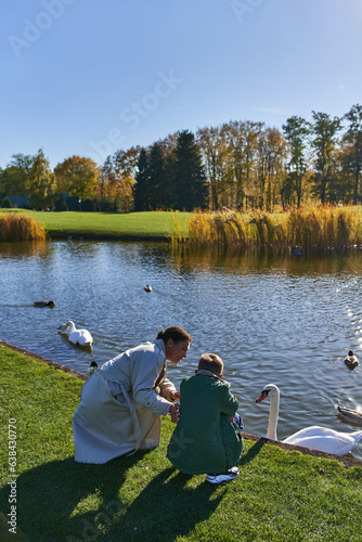 autumnal, african american woman and boy looking at lake with ducks and swans, childhood, joy
