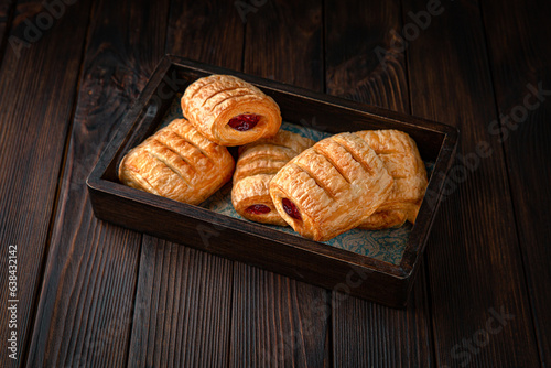Bun from puff pastry with strawberry or cherry jam on brown boards. For decoration of bakery sales outlets. Bakery products. Fresh bakery.