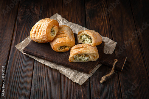 Bun from puff pastry with cottage cheese and greens on brown boards. For decoration of bakery sales outlets. Bakery products. Fresh bakery.