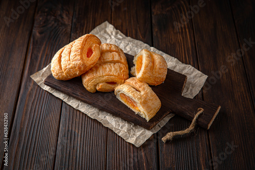 Bun from puff pastry with strawberry or cherry jam on brown boards. For decoration of bakery sales outlets. Bakery products. Fresh bakery.