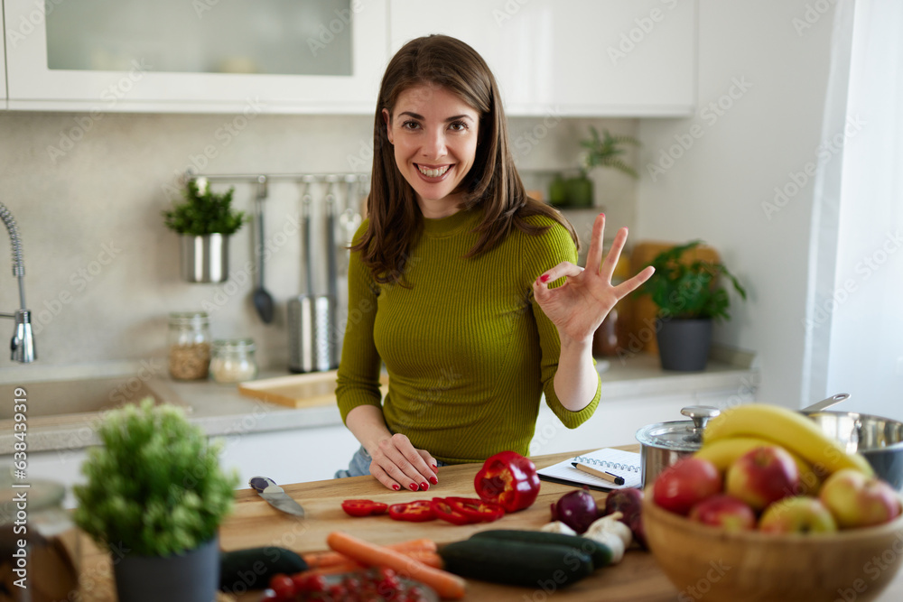 Woman chopping red bell pepper on the wooden board in the kitchen Woman chopping red bell pepper on the wooden board in the kitchen
