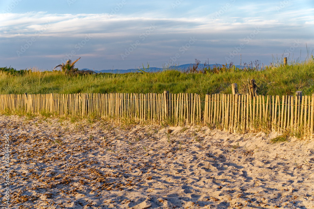 Scenic view of sandy beach with wooden fence on a blue cloudy evening at beach of Giens Peninsula. Photo taken June 8th, 2023, Giens, Hyères, France. Scenic view of sandy beach with wooden fence on a blue cloudy evening at beach of Giens Peninsula. Photo taken June 8th, 2023, Giens, Hyères, France.