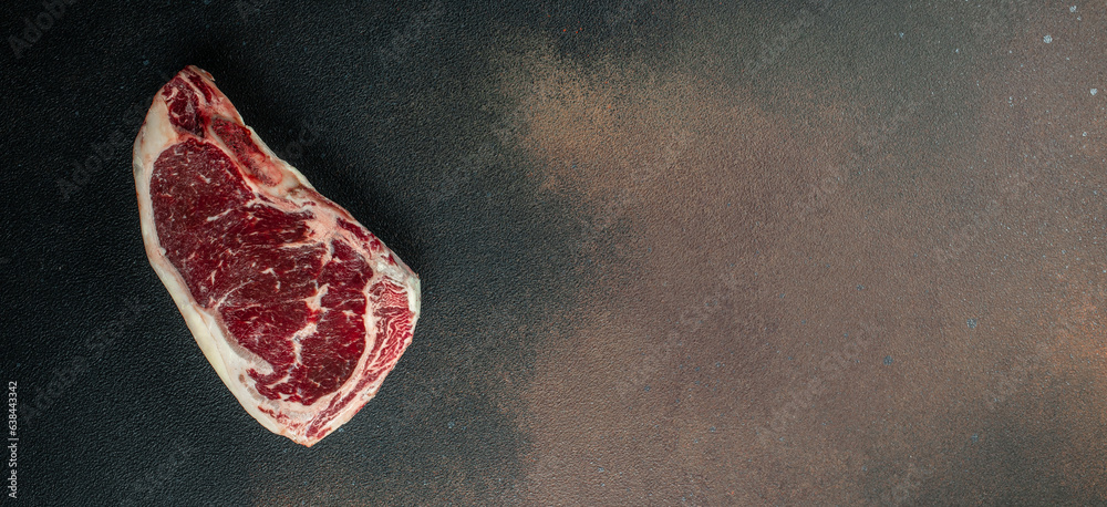 Raw New York steak on a dark background. Long banner format. top view