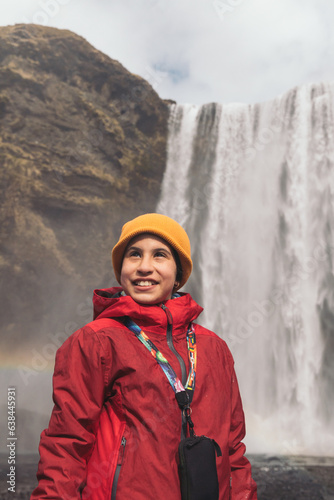 Portrait of a smiling and very happy girl with a yellow cap at Skogafoss waterfall in Iceland 