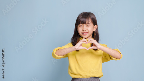 Little girl making a heart-shaped hand gesture, expressing love and happiness.