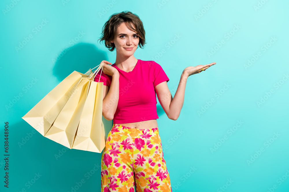 Portrait of pretty positive girl hold store bags arm hold empty space offer isolated on aquamarine color background Portrait of pretty positive girl hold store bags arm hold empty space offer isolated on aquamarine color background