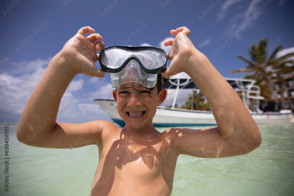 Beautiful little boy putting on mask for diving on a beach