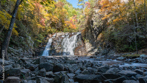 фотографія Beautiful forty-foot tall, fifty-foot-wide waterfall framed by colorful autumn foliage and river stones