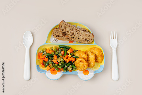 Cute plate shape of a car with children\'s dinner. Vegetables, nuggets, and bread. Creative serving for baby.  Concept of kids menu, nutrition and feeding.