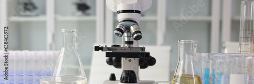 Microscope and chemical laboratory glassware on lab table.