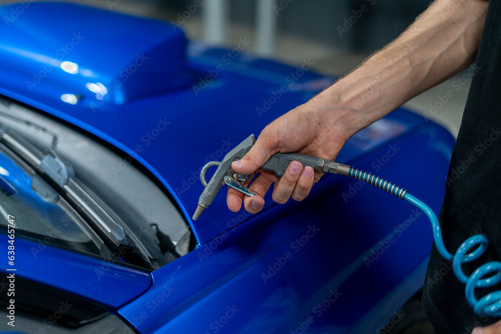 a man at a car wash uses an air compressor to dry a car