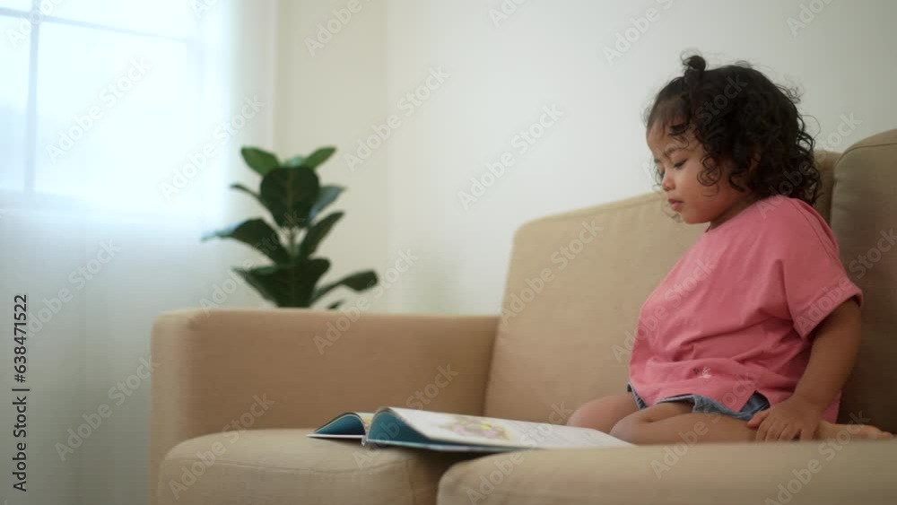 Focused little cute girl reading a book story on sofa in living room at home. Kids activity learning. Emotional, Cognitive development concept.
Focused little cute girl reading a book story on sofa in living room at home. Kids activity learning. Emotional, Cognitive development concept.