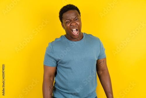 Young handsome man standing over yellow studio background winking looking at the camera with sexy expression, cheerful and happy face.