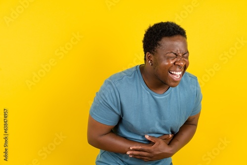 Young handsome man standing over yellow studio background smiling and laughing hard out loud because funny crazy joke with hands on body.
