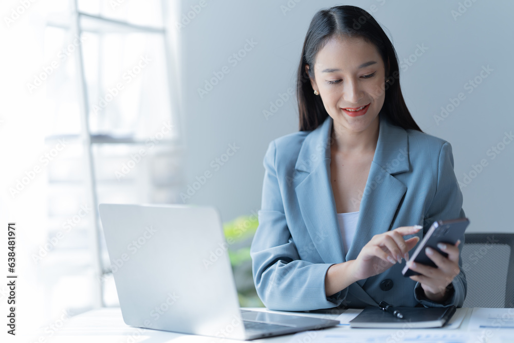 Portraits of beautiful Asian businessmen, women working in a startup company office, managing a growing and profitable company. Business management use smartphone and laptop.