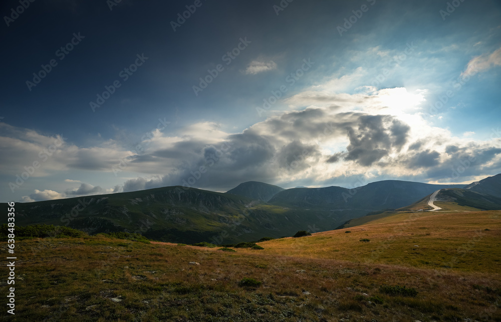 Sunset over Transalpina waving curved road in Romania. Beautiful landscape from Parang mountains during a spectacular summer sunset view. Travel to Transylvania.