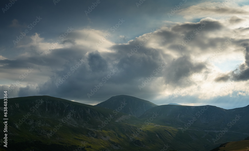 Sunset over Transalpina waving curved road in Romania. Beautiful landscape from Parang mountains during a spectacular summer sunset view. Travel to Transylvania.